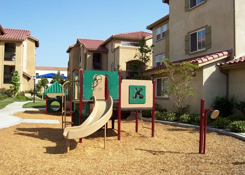 A playground with a slide and a sign with an 'X' on it.