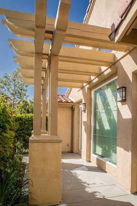 A long wooden pergola overhangs a patio.