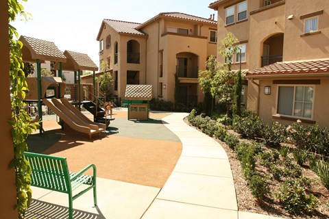 A playground area with a green slide and a bench.