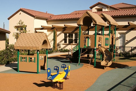 A playground with a yellow and blue slide and a green and yellow swing set.
