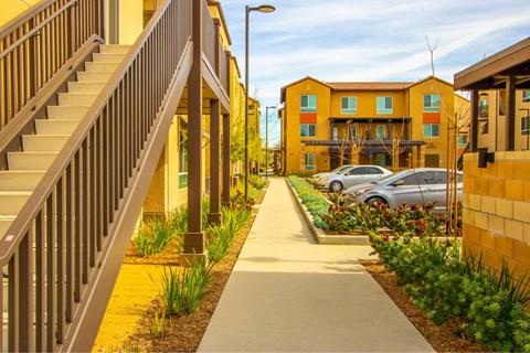 A long concrete walkway leads to a building with a staircase on the left.