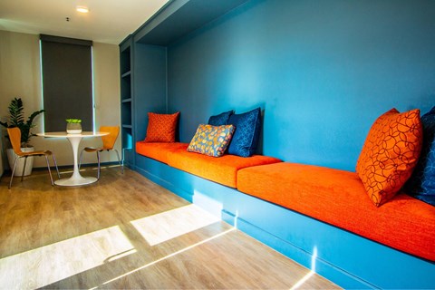 A blue wall with a red couch and pillows.