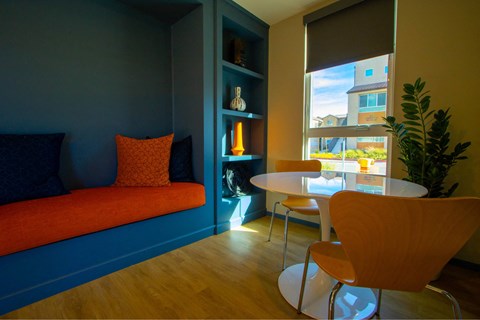 A living room with a blue couch and orange pillow.