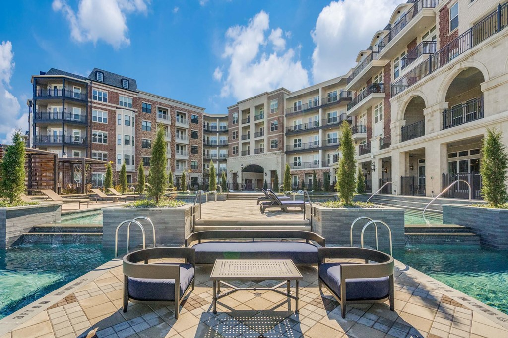 a swimming pool with furniture and a building in the background