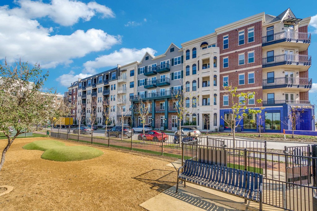 a park with a bench in front of an apartment building