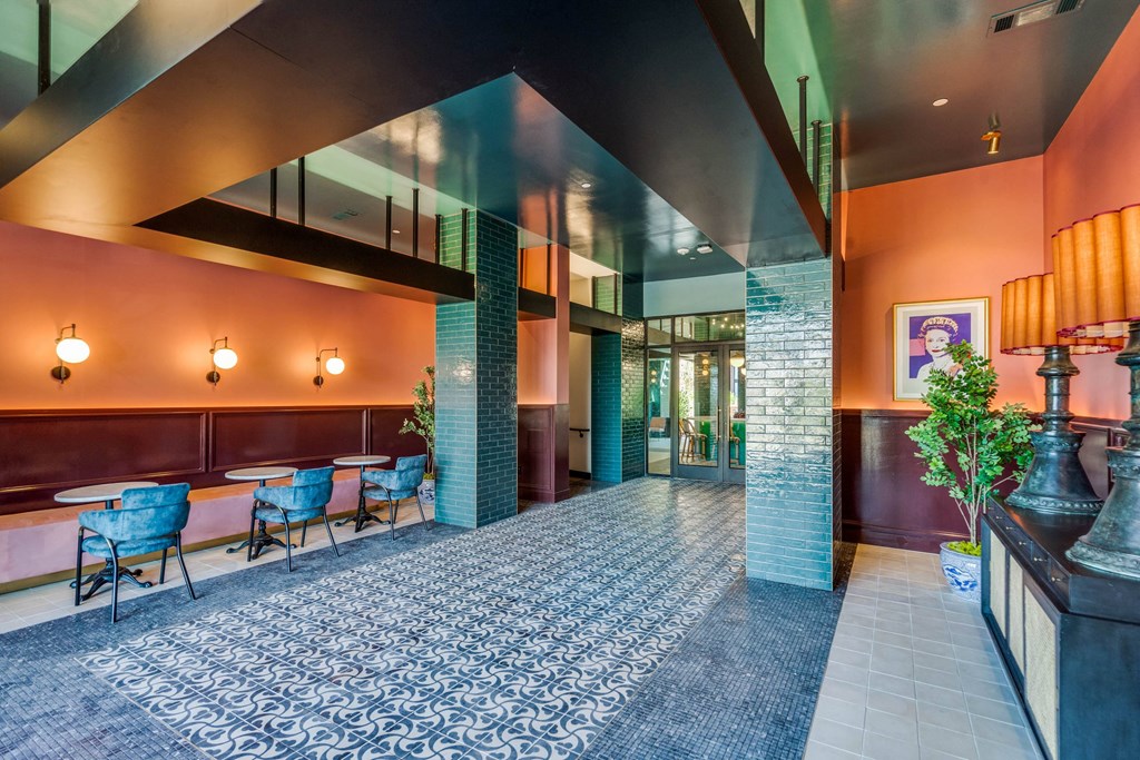a large lobby with tables and chairs and orange walls