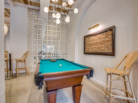 A pool table with a green cloth and a wooden frame is in the center of the room.