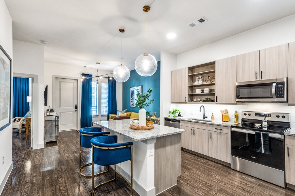 an open kitchen with a large island with blue chairs