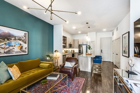 a living room with a yellow couch and a kitchen with a blue wall