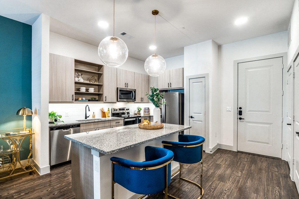 a kitchen with a marble counter top and blue chairs