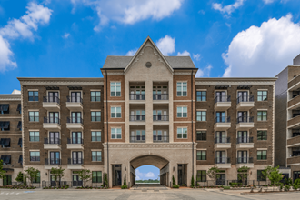 a large apartment building with an archway in the middle of a parking lot