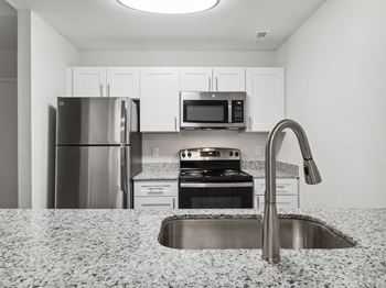 A kitchen with a sink, stove, and refrigerator.