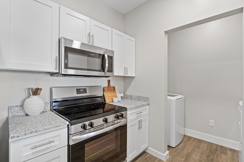 A kitchen with white cabinets and a stove top oven.