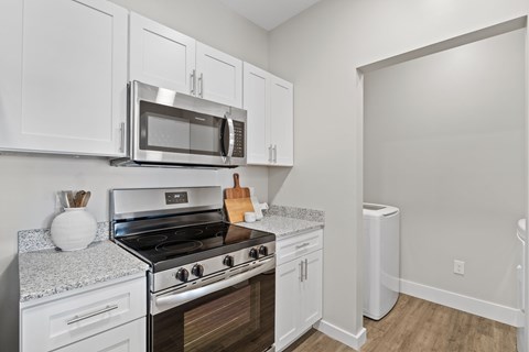 A kitchen with white cabinets and a stove top oven.