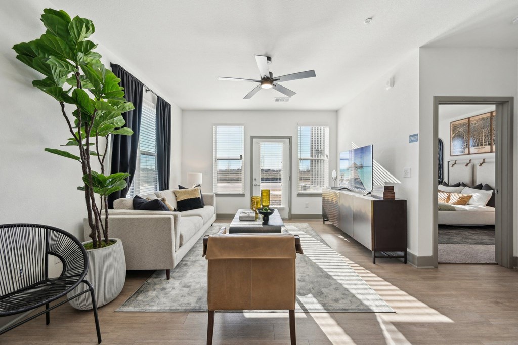 A living room with a white couch, a wooden table, and a ceiling fan.