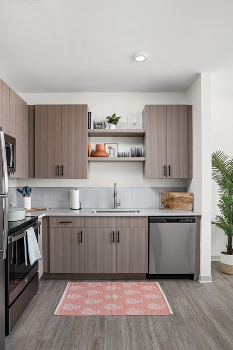 A modern kitchen with wooden cabinets and a red rug on the floor.