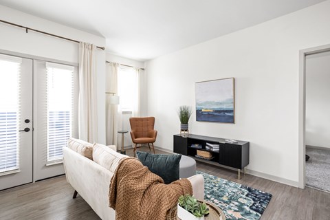 A living room with a white couch, a brown chair, and a painting on the wall.