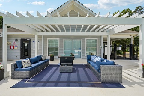 A patio with a white pergola and blue cushions.
