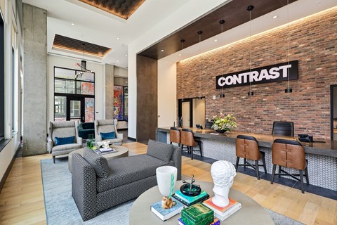 A living room with a grey couch and a brick wall with the word CONTRAST on it.