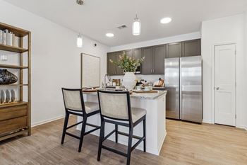 a kitchen with stainless steel appliances and a bar with two chairs  at Plat 4 at Research Triangle, Durham
