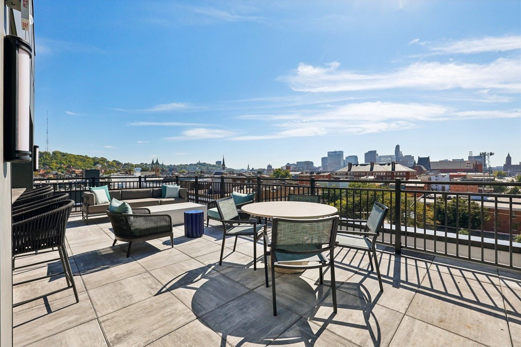 A balcony with a table and chairs overlooking a city skyline.