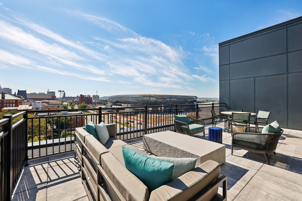 A balcony with a couch and chairs overlooking a cityscape.