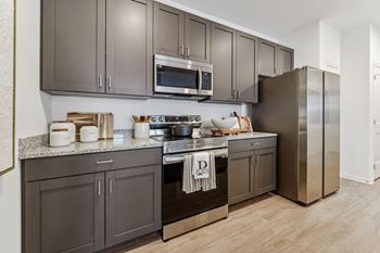 a kitchen with stainless steel appliances and gray cabinets  at Plat 4 at Research Triangle, North Carolina