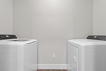 Two white front load washing machines in a laundry room.