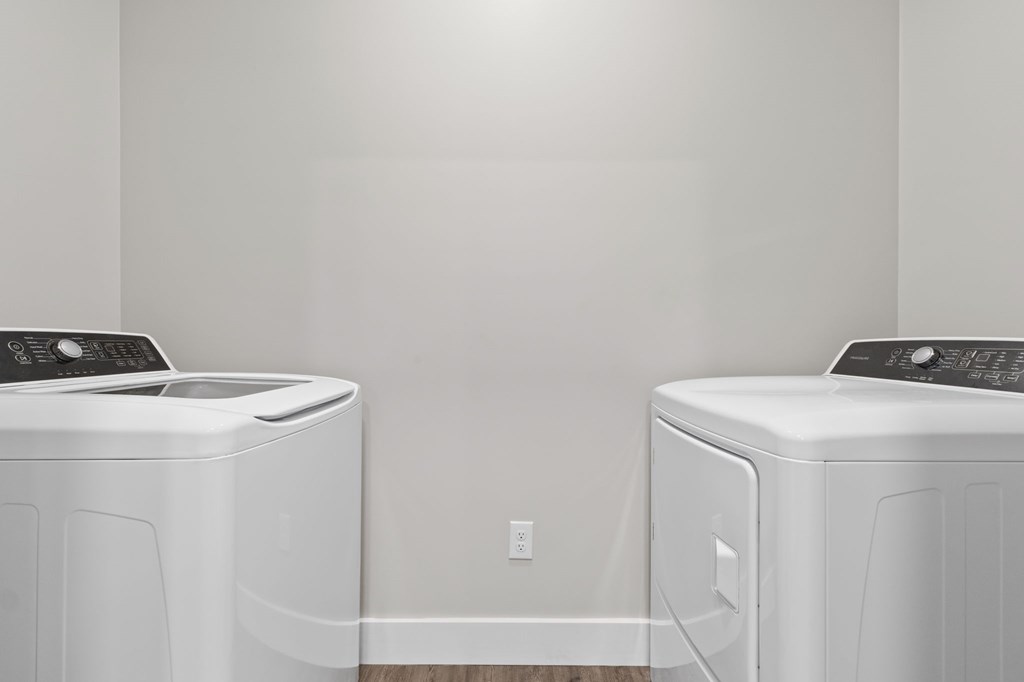 Two white front load washing machines in a laundry room.