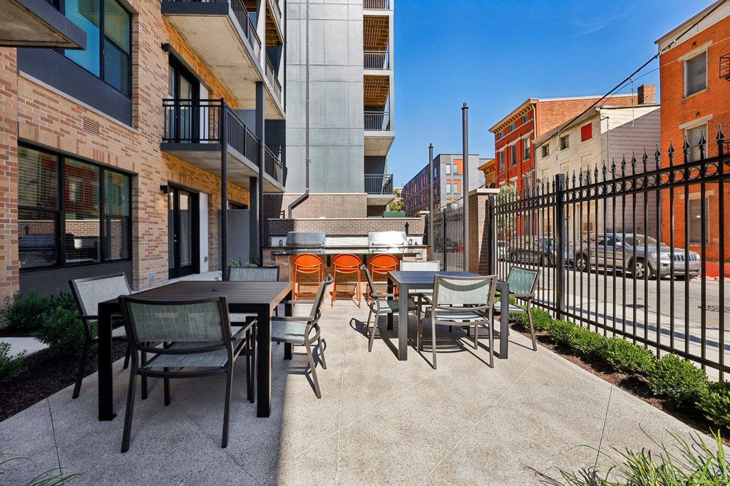 Outdoor courtyard at Contrast OTR in Cincinnati, OH with grills, dining tables, and bright orange lounge seating.