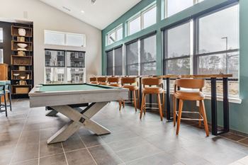 Billiards In Clubhouse a clubhouse with a pool table and a bar with chairs