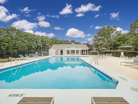 a pool with lounge chairs and a house in the background