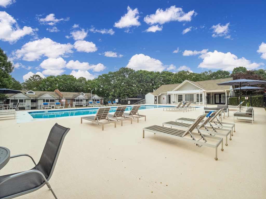 a pool with lounge chairs and umbrellas at the enclave at woodbridge apartments in sugar