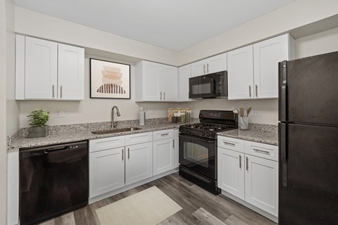 a kitchen with white cabinets and black appliances