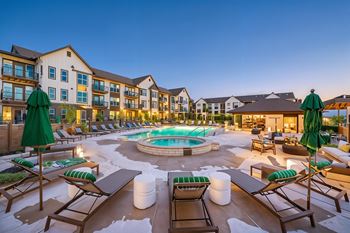 A large outdoor pool area with lounge chairs and umbrellas.