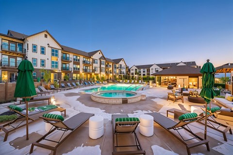 A large outdoor pool area with lounge chairs and umbrellas.
