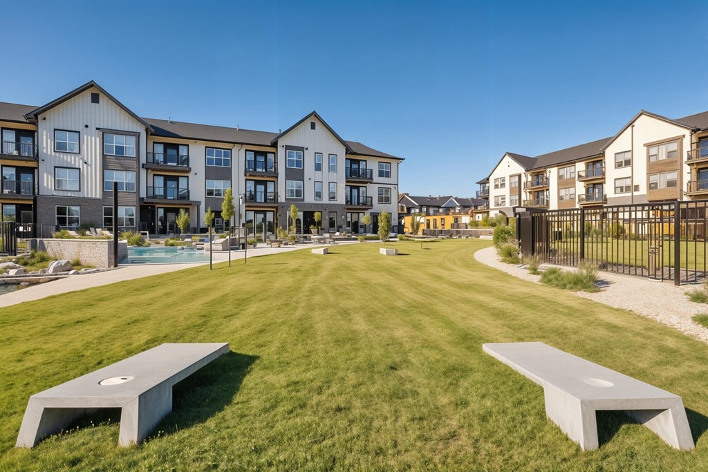 A park with benches and apartment buildings in the background.