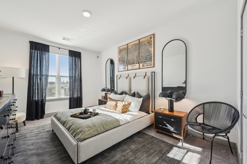 A bedroom with a large bed and a chair.