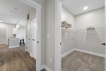 A white closet with clothes hanging on the rack.