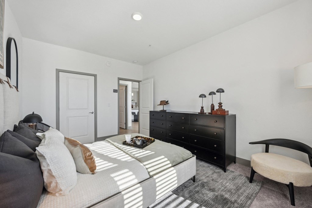 A bedroom with a bed, dresser, and chair.