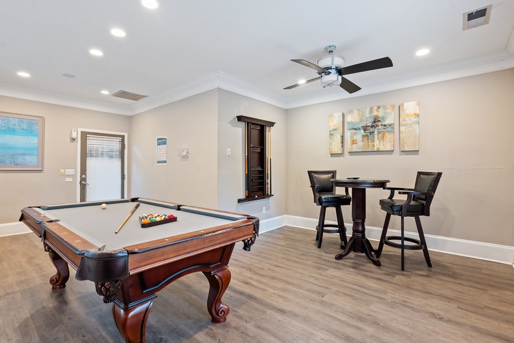 Billiards room with pool table and seating at Village at Almand Creek apartments.