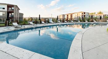 A large outdoor swimming pool with lounge chairs and a fence around it at Echo Park at Perry Crossing Apartments, Plainfield, IN, 46168