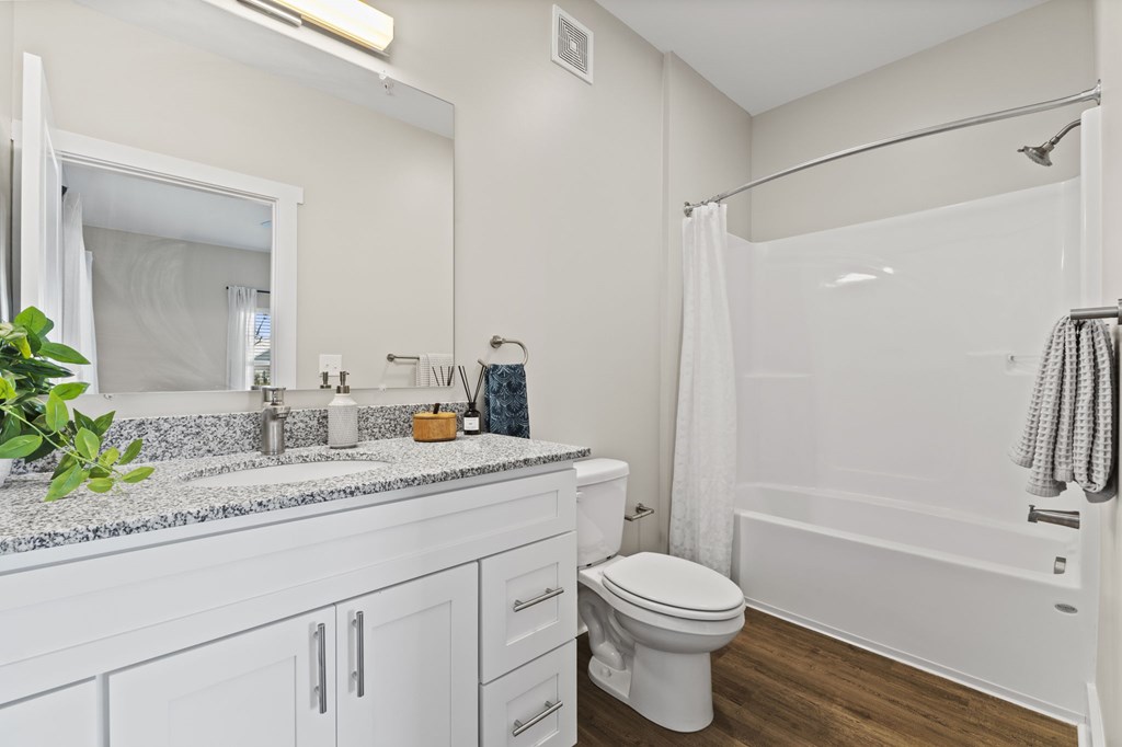 A white bathroom with a toilet, sink, and shower.