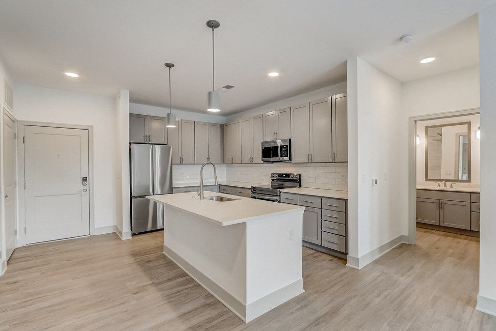 a white kitchen with a large island and stainless steel appliances