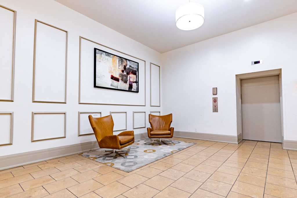 a lobby with two chairs and a painting on the wall at 26 West, Managed by Buckingham Urban Living, Indianapolis