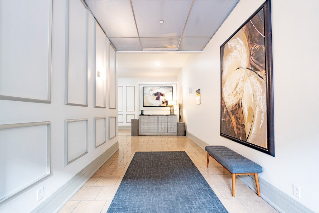 a view down a hallway with a bench and a large painting on the wall at 26 West, Managed by Buckingham Urban Living, Indianapolis