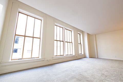 an empty living room with three large windows