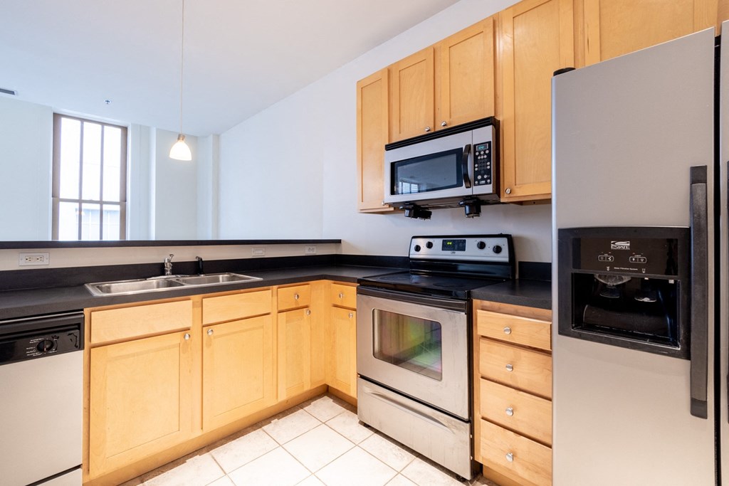 a kitchen with wooden cabinets and stainless steel appliances at 26 West, Managed by Buckingham Urban Living, Indianapolis