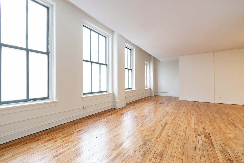an empty living room with hardwood floors and large windows at 26 West, Managed by Buckingham Urban Living, Indianapolis