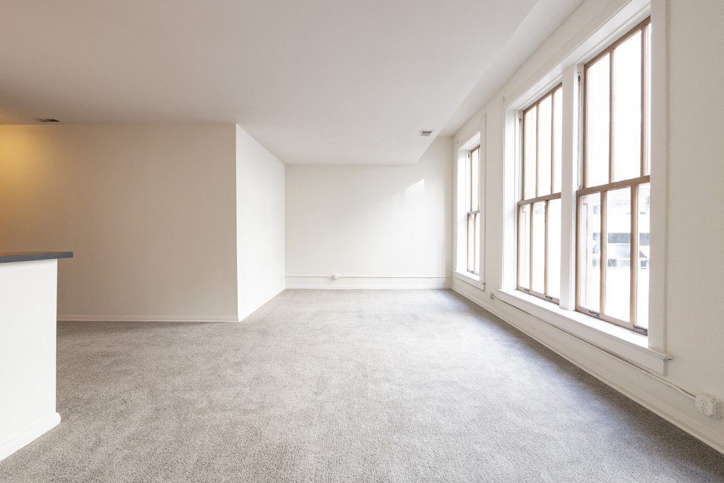 an empty room with large windows and a carpeted floor at 26 West, Managed by Buckingham Urban Living, Indianapolis